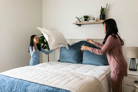 
      A mom and daughter throwing a pillow at each other while making their zipper bedding.
    