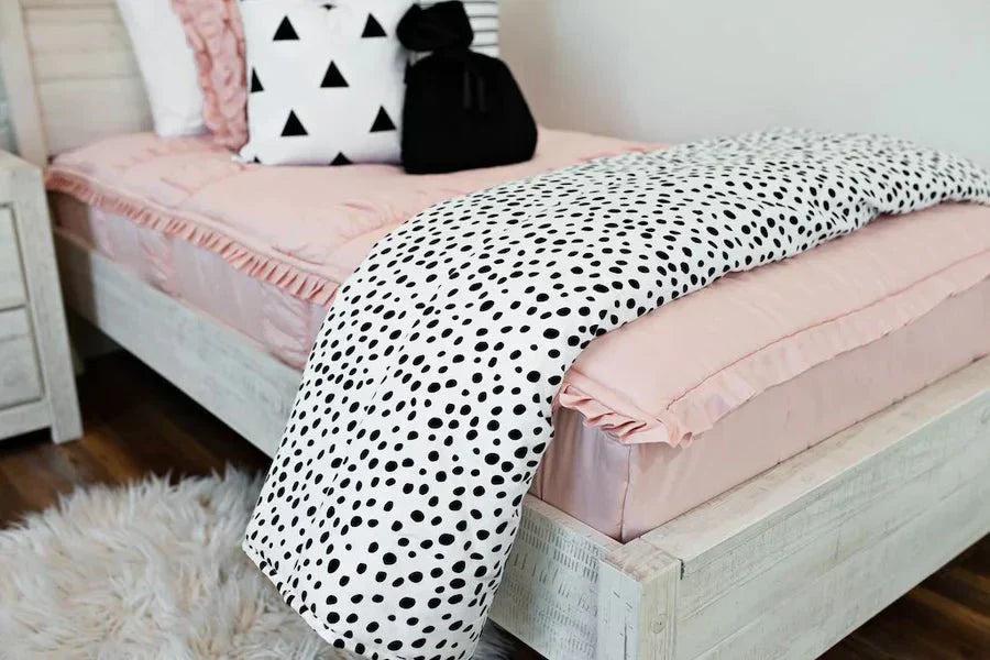 
      A twin bed made with pink zipper bed and black and white accessories.
    