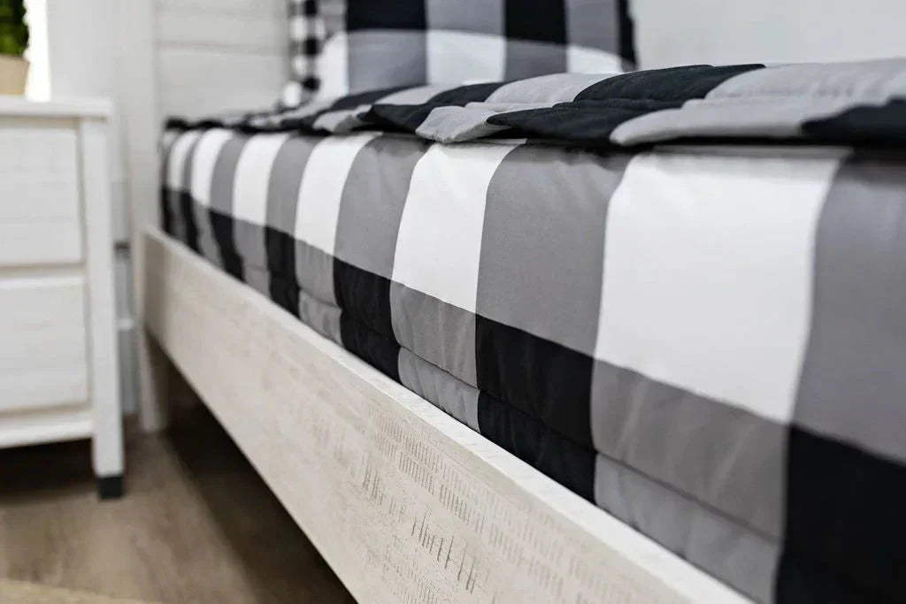 
      A low side shot of a bed made with black and white checked zipper bedding.
    