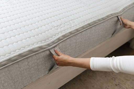 
      hands pulling down on mattress flaps to check for sagging
    