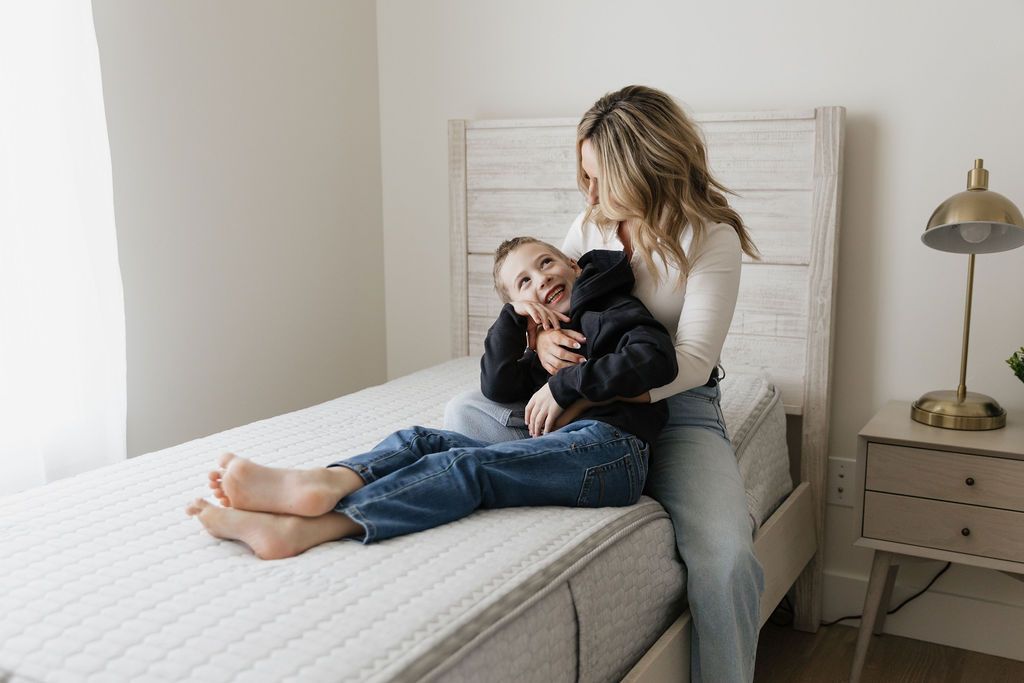 A mother sitting on a zipper mattress holding her 8 year old son in their lap.