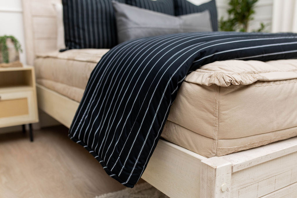 Black striped blanket on tan zipper bedding, with coordinating pillows
