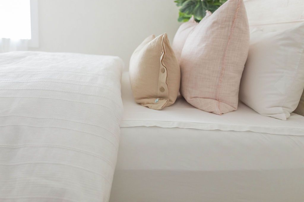 White duvet with white, pink and tan pillows on bed
