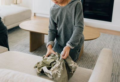 A boy putting his dino print blanket inside the coordinating dino print bag.