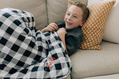 Little boy cuddling on couch with white, black and gray child's blanket 