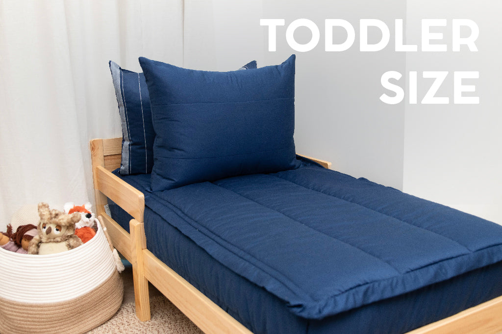 A toddler bed made with navy blue zipper bedding.