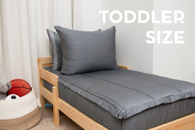 A toddler bed made with gray zipper bedding.
