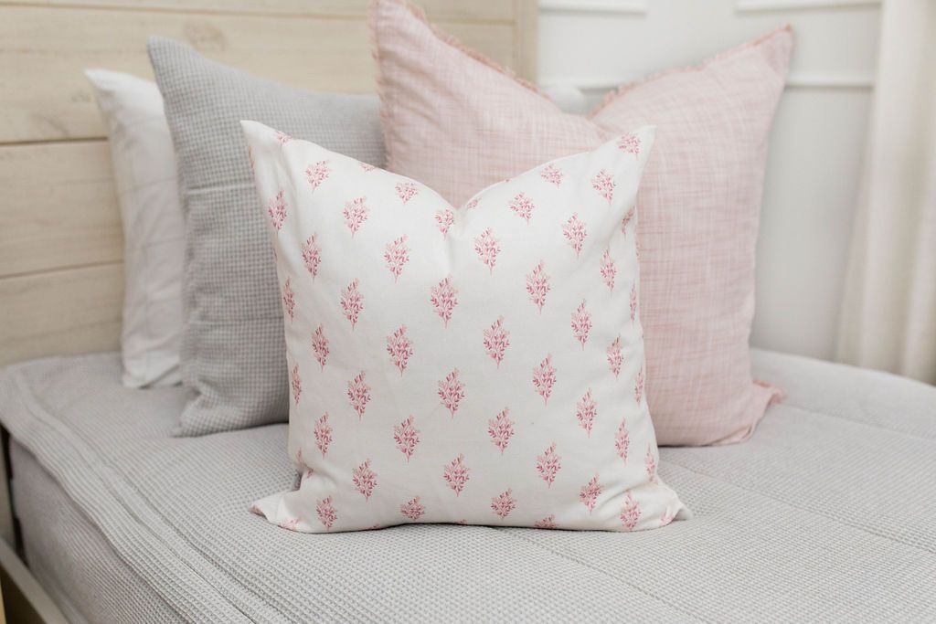 white pillow with pink floral design, pink euro on gray bedding