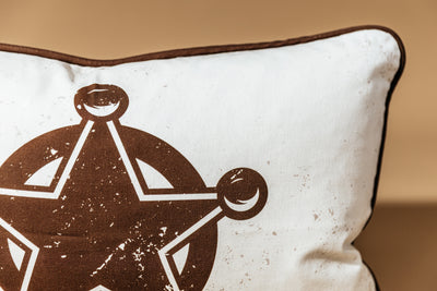 A close up of the star print on a western pillow arranged on a brown backdrop.