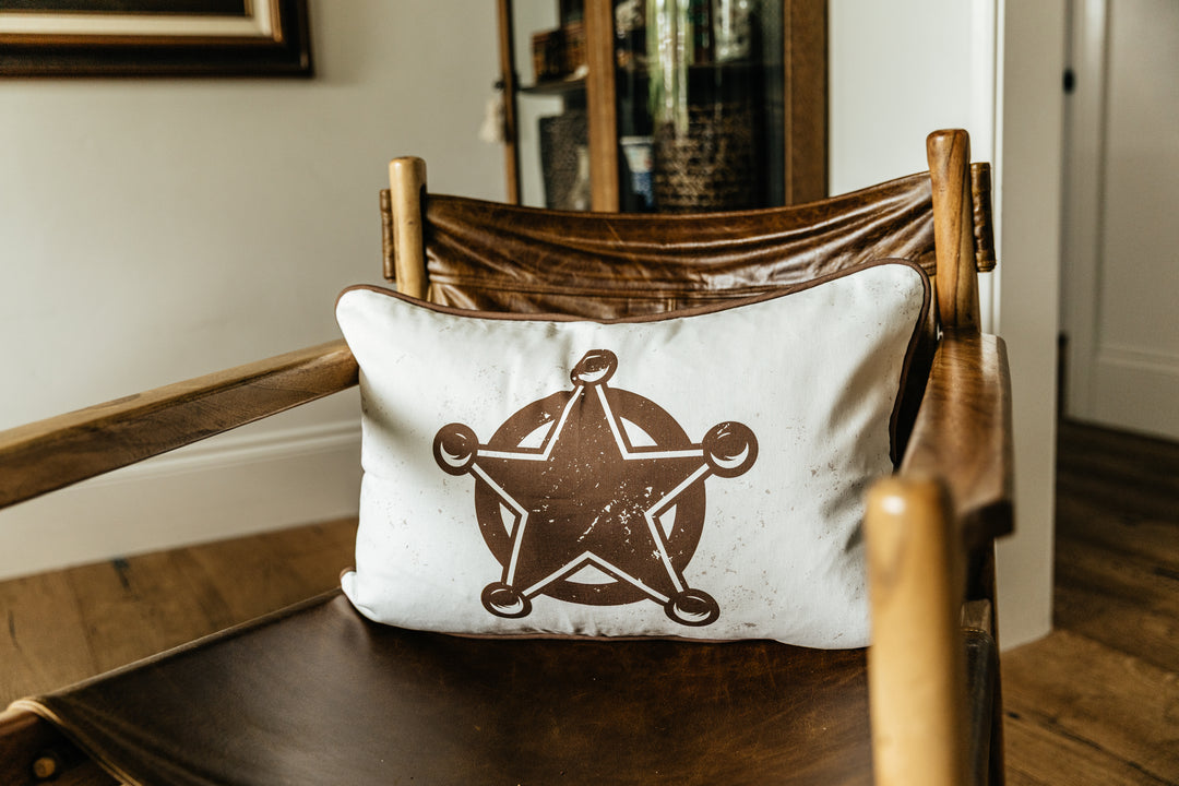 A western print pillow on a leather chair in a living room.