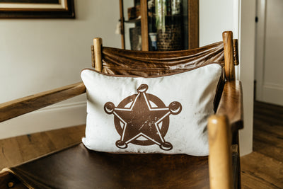 A western print pillow on a leather chair in a living room.