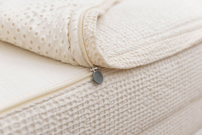 A close up of the zipper feature on a set of cream waffle knit zipper bedding.