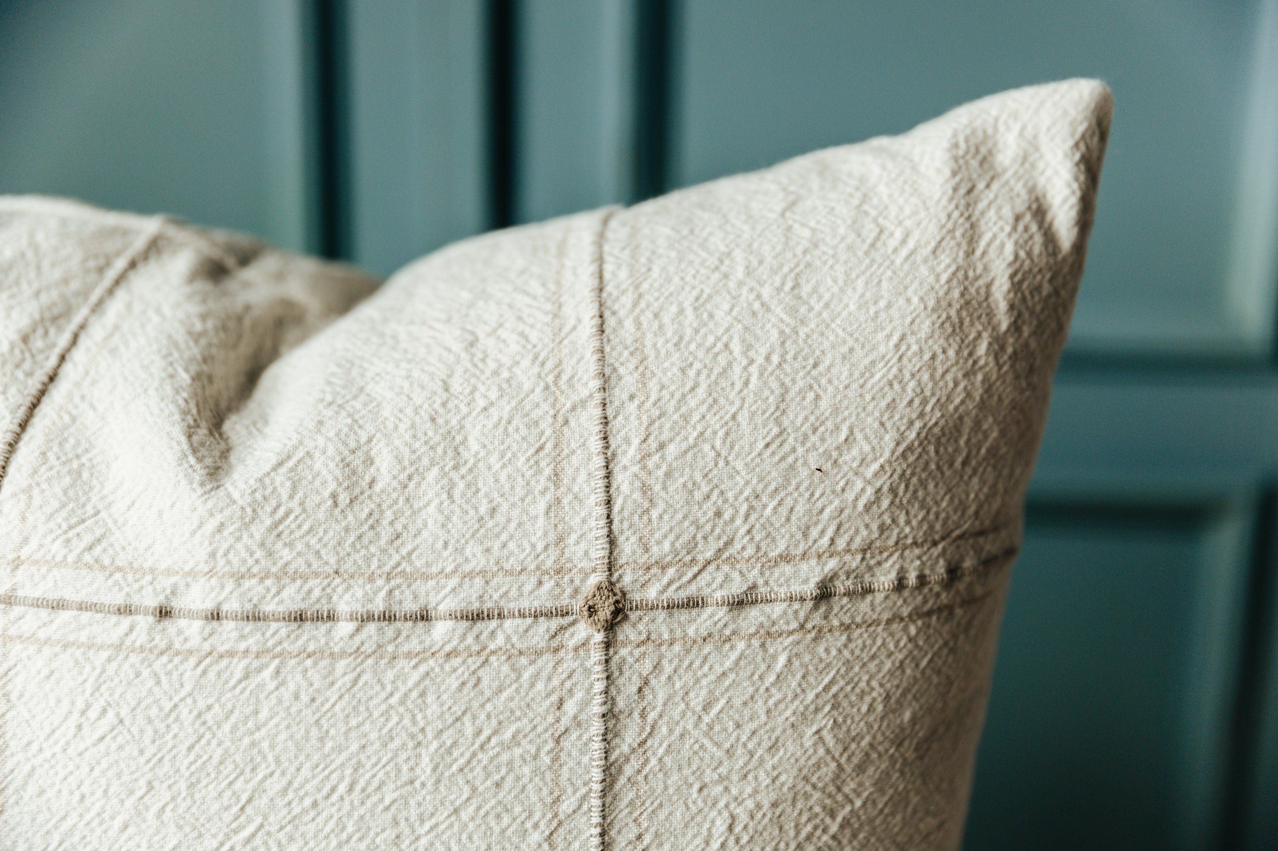 A close up shot of a neutral plaid pillow cover to show the textured detail and plaid design of the pillow.