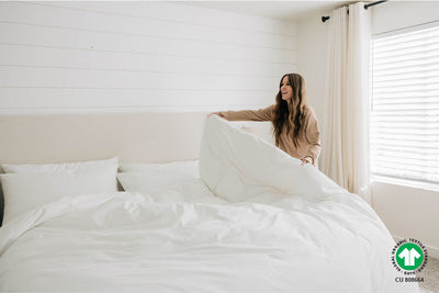 Woman making king bed with organic duvet