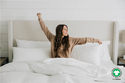 Woman stretching in king bed with organic bedding