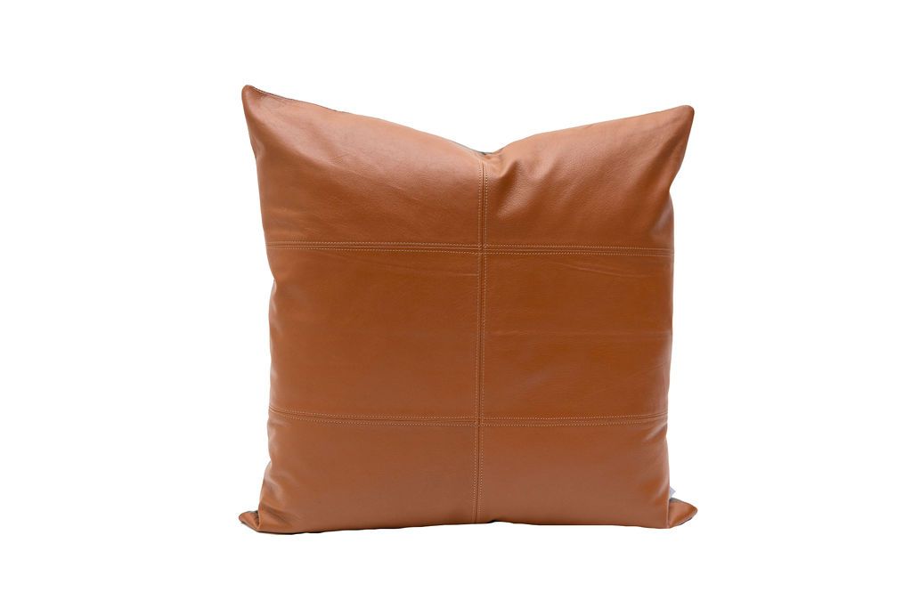 A large brown leather pillow on a white background. 