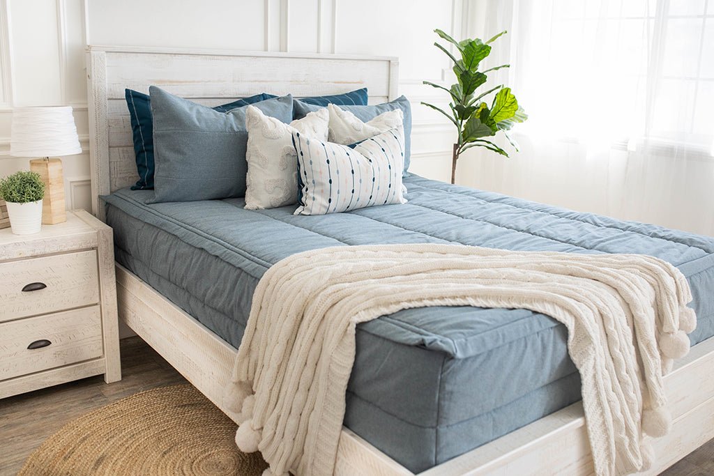 Blue zipper bedding styled with Blue and cream pillows and cream throw blanket