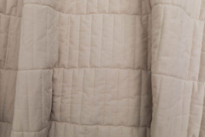 A close up view of a tan quilted blanket.