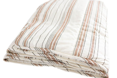 A folded white blanket with black and cognac striped pattern design.