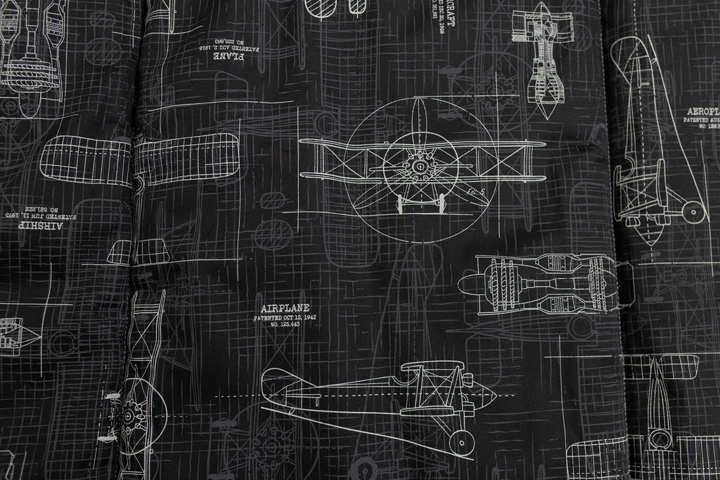 A close up view of a black charcoal airplane patterned blanket.