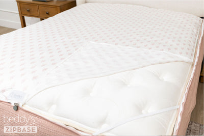 A ZipBase sheet partially unzipped and pulled back to show how it detaches from the rest of the base sheet wrapped around the sides of the mattress.