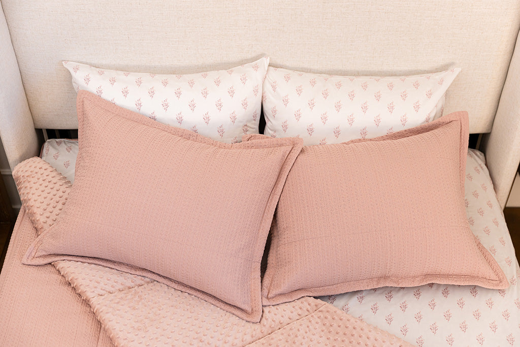 Overhead photo of pink knitted zipper bedding with pink floral bed sheets and pink minky interior.
