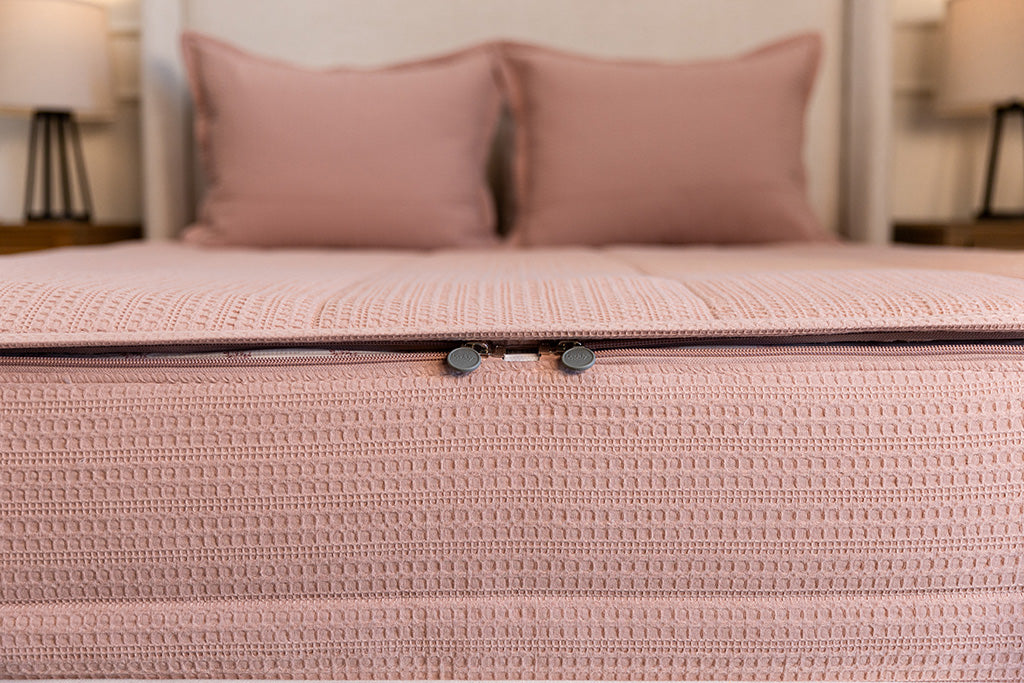 End of bed showing double zippers on pink knitted zipper bedding.