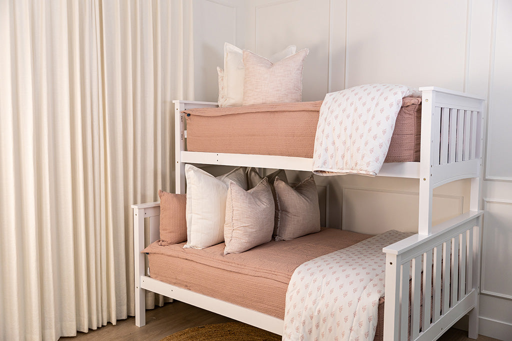 A bunk bed made with pink knitted zipper bedding with pink and white accessories.
