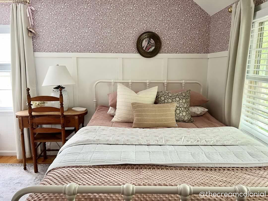 A bed made with woven pink zipper bedding and an assortment of neutral pillows and blankets.