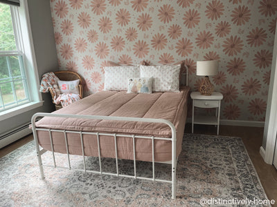A bed made with woven pink zipper bedding and pink floral pattern pillows.