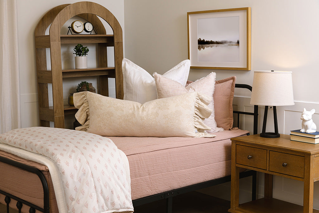 Twin bed with pink knitted zipper bedding with pink, cream, and white accessories.