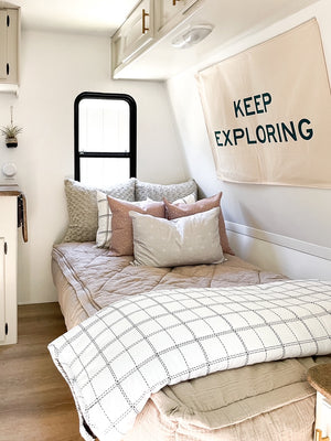 Cream zipper bedding styled with matching pillows and blanket in RV