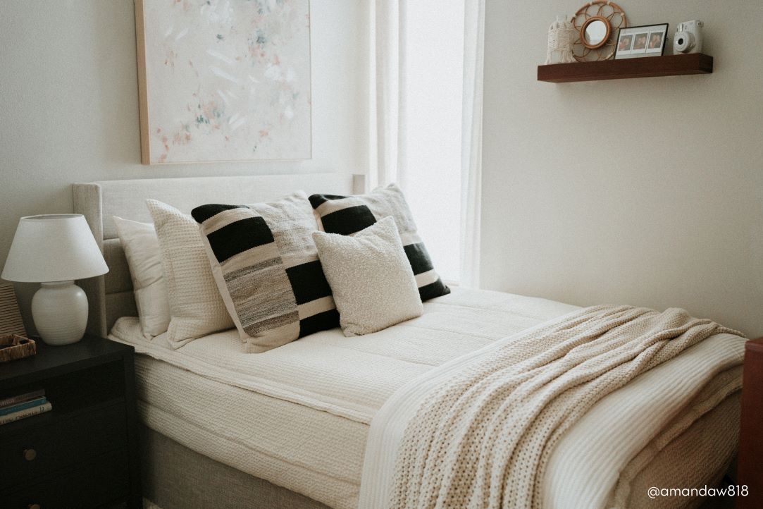 A full bed made with cream waffle textured zipper bedding and an assortment of neutral pillows and blankets.