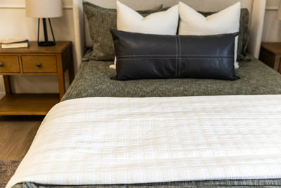 White blanket on green zipper bedding with white and charcoal accessories