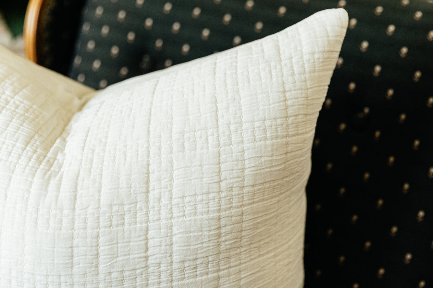 Corner shot of white textured cotton pillow on chair