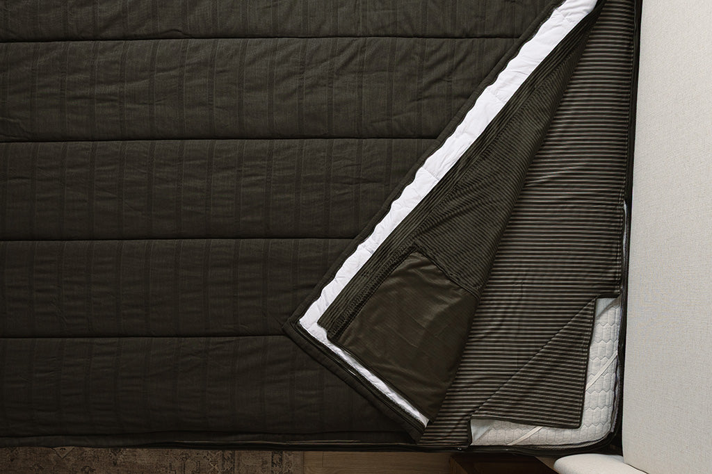 Overhead shot of black knit texture zipper bedding layers.