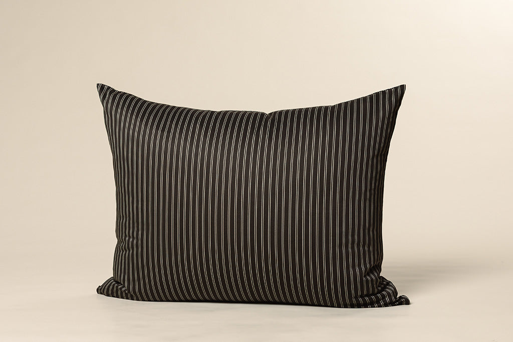 A black and tan striped printed pillowcase on a cream backdrop.