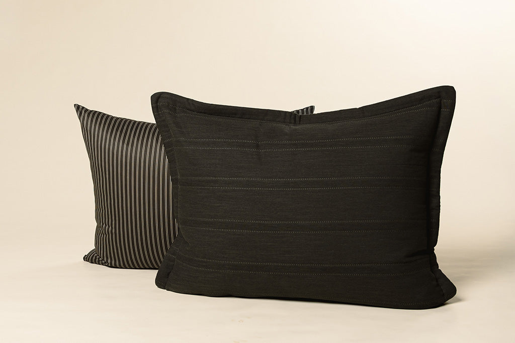 A black and tan striped pillowcase with a black sham on a cream backdrop.