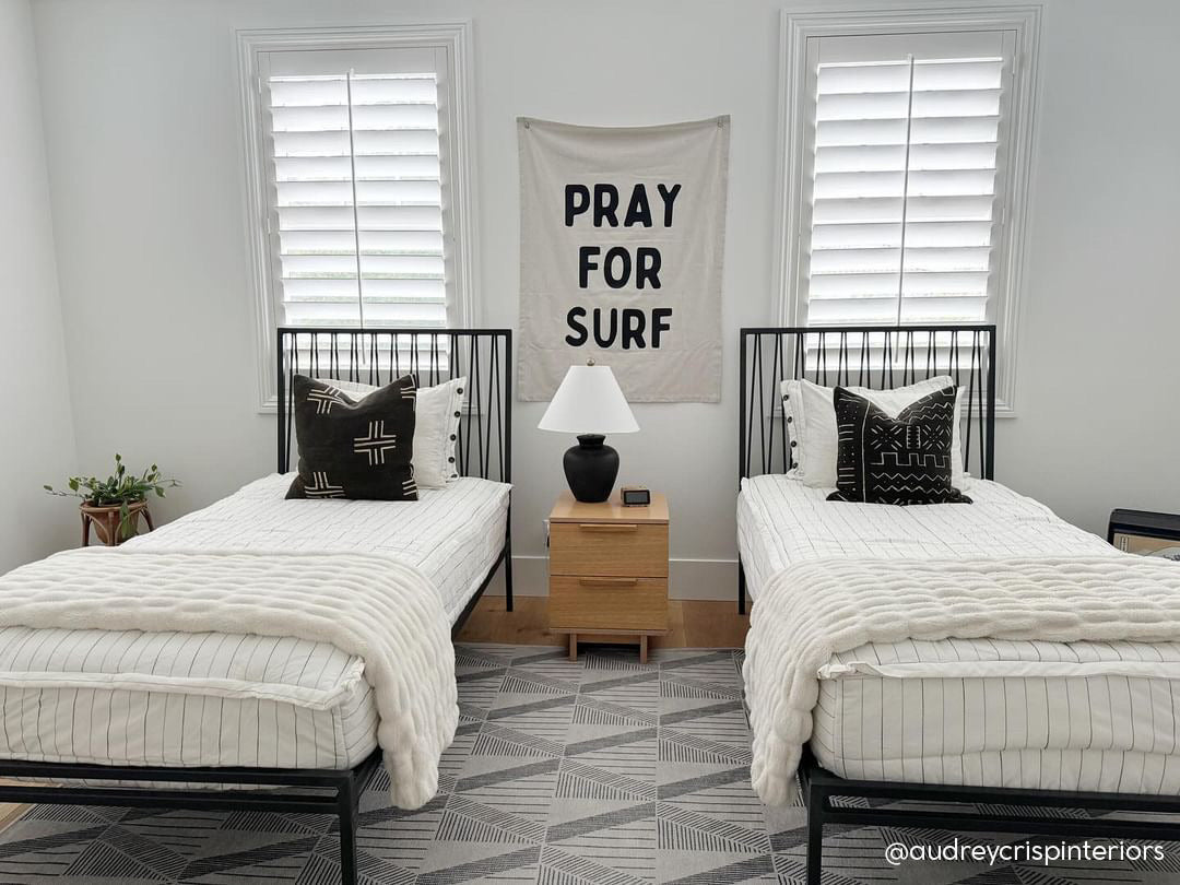 Two twin beds made with white and pinstripes zipper bedding and black pillows and white puffy blankets. 