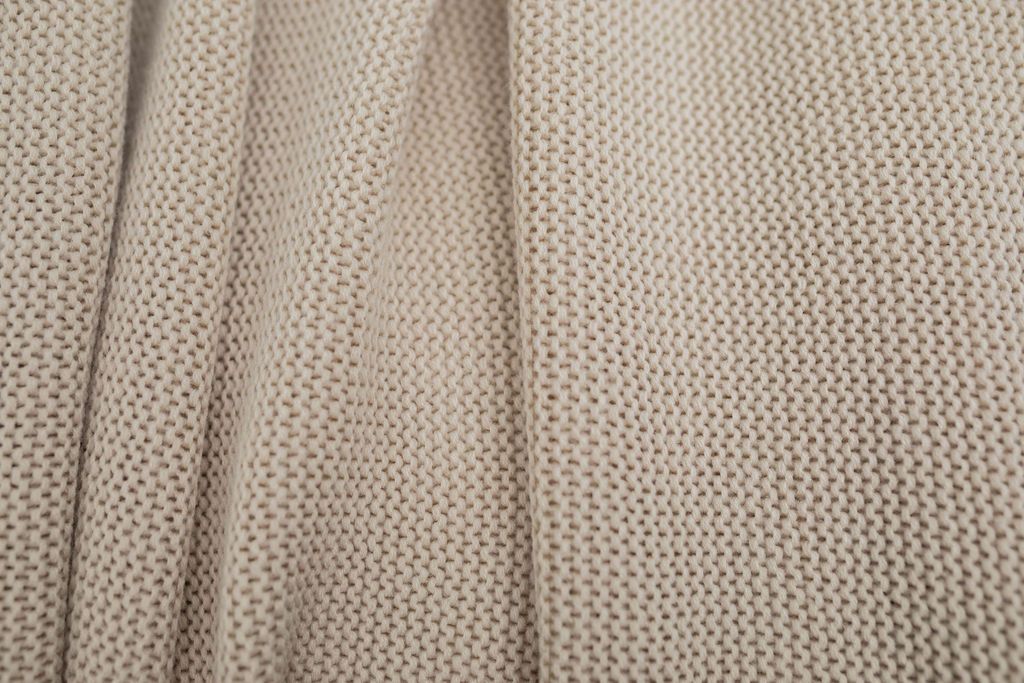 A close up of a tan woven textured blanket.