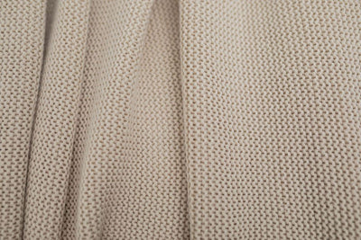 A close up of a tan woven textured blanket.