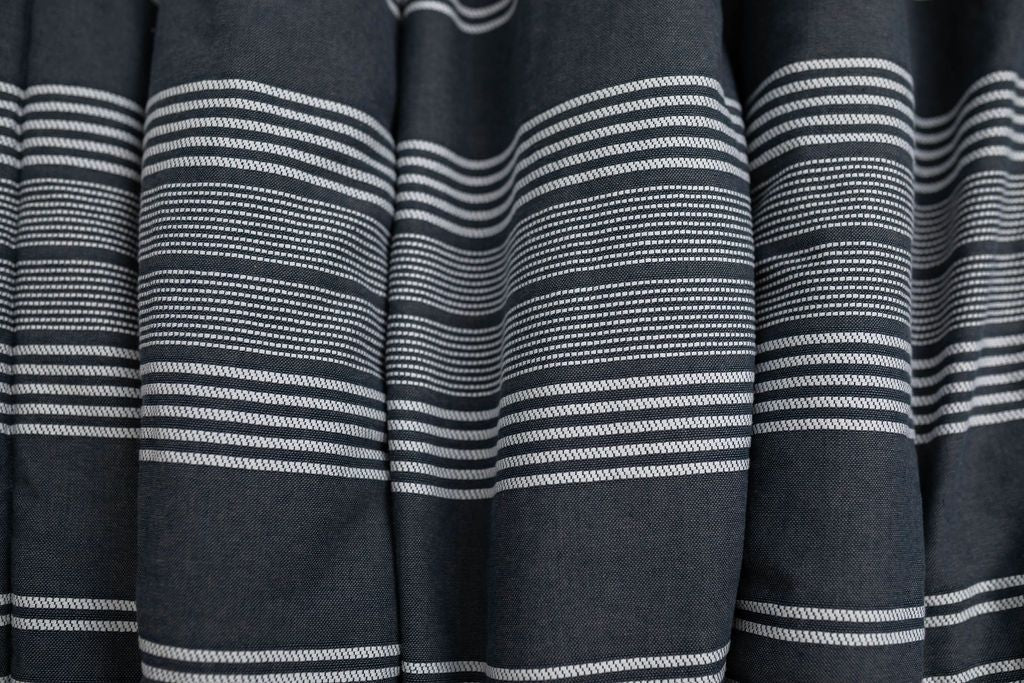 A close up of a woven white and charcoal gray striped pattern blanket.