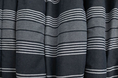 A close up of a woven white and charcoal gray striped pattern blanket.