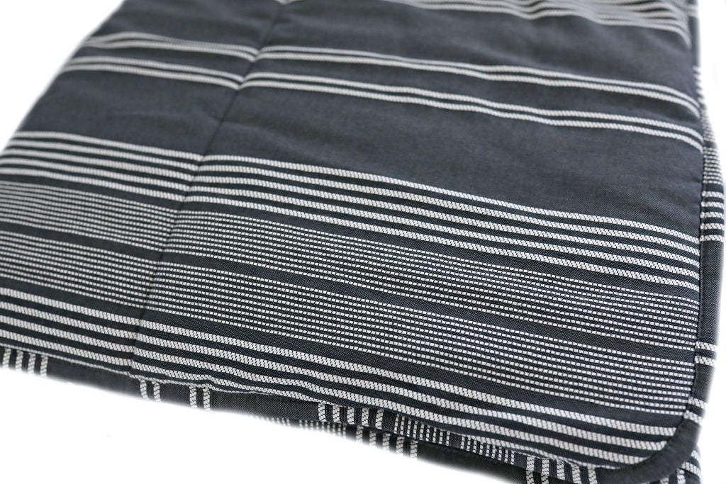 A folded woven white and charcoal gray striped pattern blanket.
