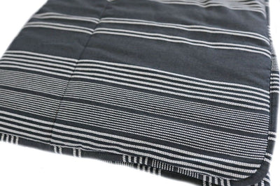 A folded woven white and charcoal gray striped pattern blanket.