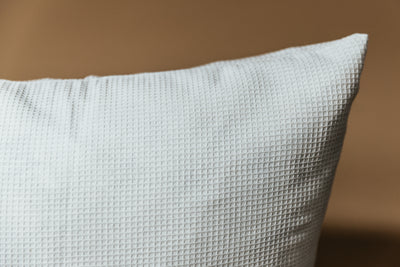 A close up on a light gray pillow to showcase the waffle texture on the exterior.