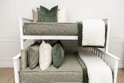 A standard bunk bed with both bunks made with deep emerald green zipper bedding and white pattern and green velvet pillows and blankets.