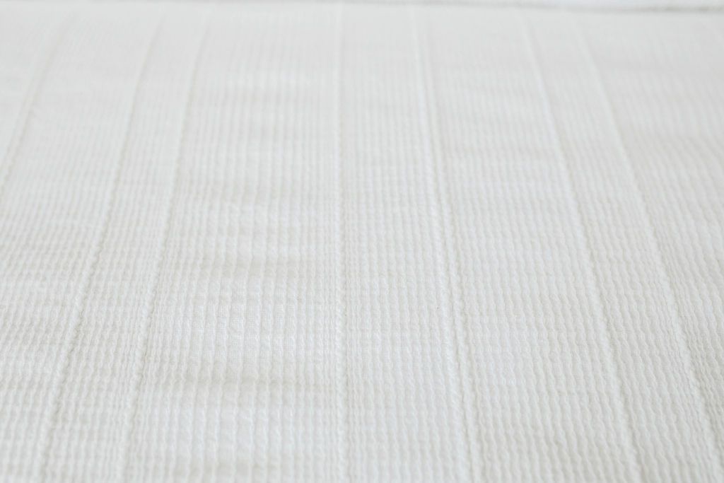 A close up view of the textured woven detailing on a white zipper duvet.