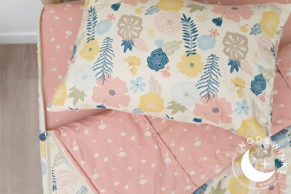 A twin bed made with yellow, pink, and blue floral kids zipper bedding, the top unzipped and slightly pulled back and a pillow on the bed.