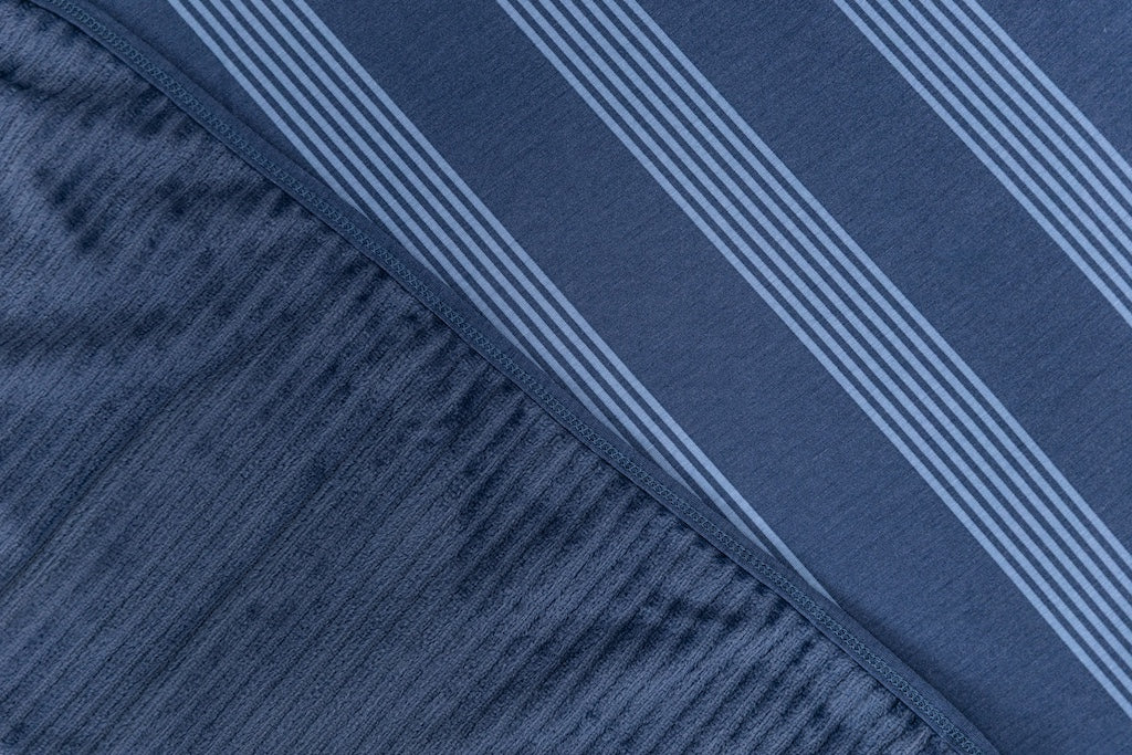 A close-up front and back view of a blue stripe printed travel blanket. 